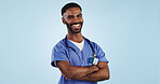 Happy man, portrait and professional doctor with arms crossed in medical care against a blue studio background. Male person, nurse or confident surgeon smile with stethoscope for healthcare on mockup