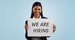 Business woman, portrait and hiring sign for advertising opportunity or deal against a blue studio background. Female person smile with billboard or poster in job recruiting or career on mockup space