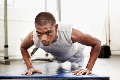 Buy stock photo Seriously focused man doing push ups in a gym