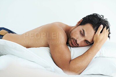 Buy stock photo Thinking, relax and shirtless with a sexy man lying on a bed in studio on a white background. Tattoo, idea and topless with a handsome young male model posing in a bedroom for sensuality or desire