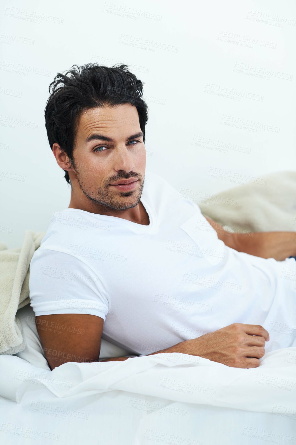 Buy stock photo Portrait, relax and bed with a sexy man in the morning on a white background looking casual after wake up. Fashion and confidence with a handsome young male model lying in the bedroom of his home