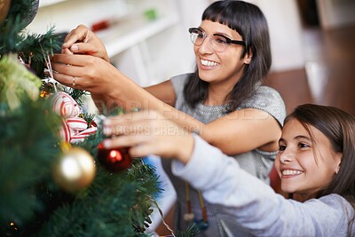 Buy stock photo Shot of a mother and daughter hanging Christmas decorations on a tree