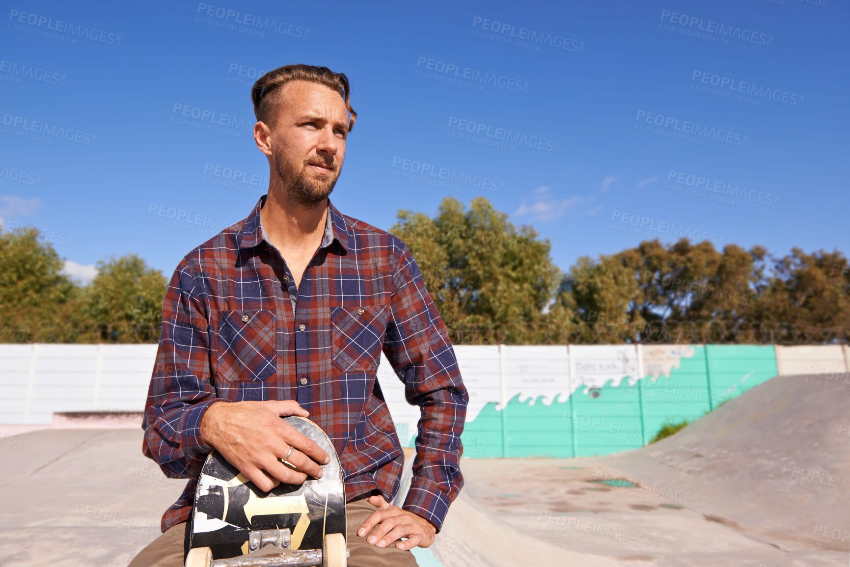 Buy stock photo Shot of a young man sitting with his skateboard