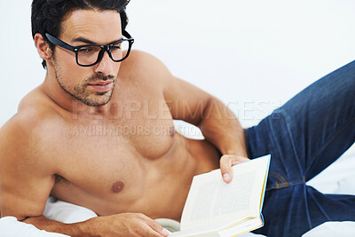 Buy stock photo Relax, glasses and a shirtless man reading a book in the bedroom of his apartment for hobby or leisure. Thinking, storytelling and the body of an intelligent young person lying on the bed of his home
