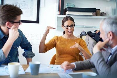 Buy stock photo Shot of a young businesswoman explaining something to her colleagues in a meeting