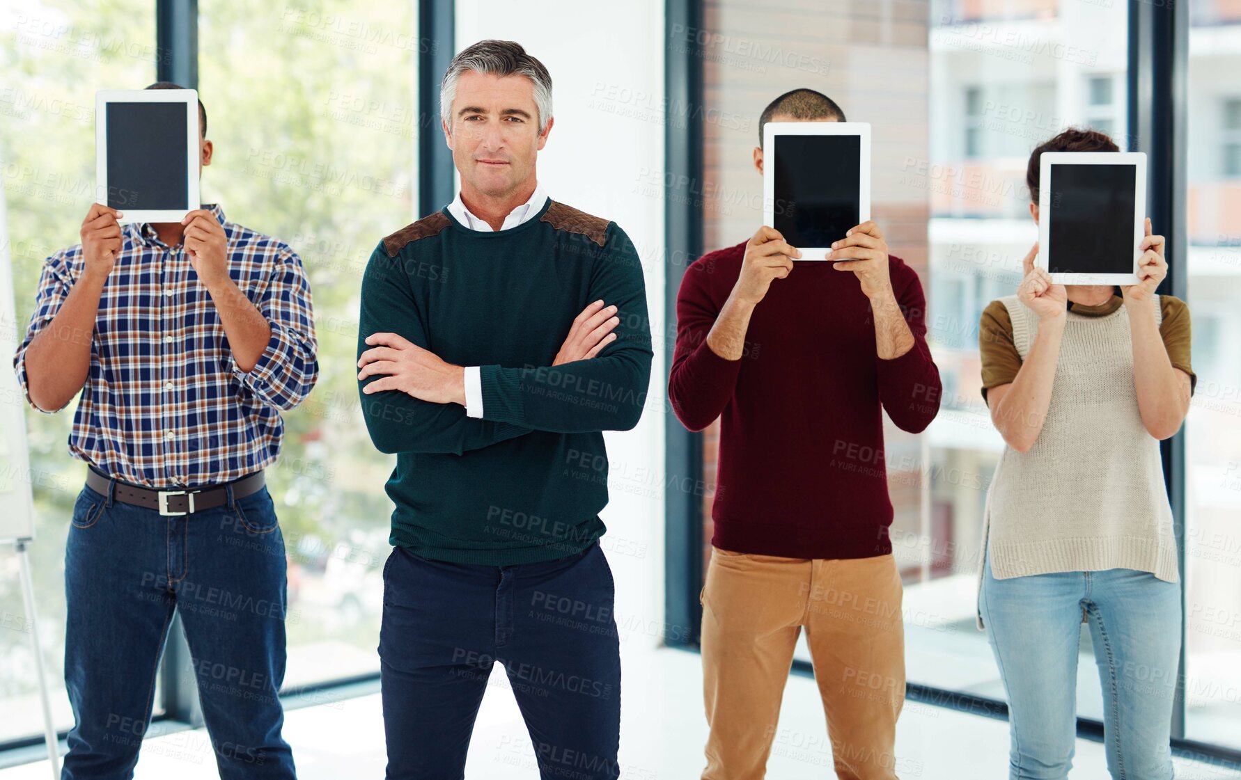 Buy stock photo Cropped portrait of a mature businessman standing with his colleagues who are covering their faces with tablets