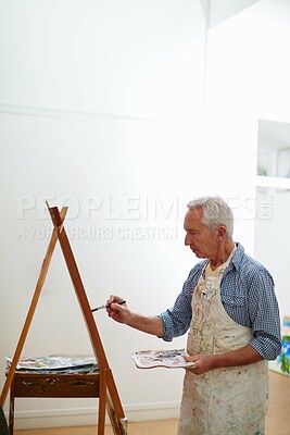 Buy stock photo Shot of a senior man working on a painting at home