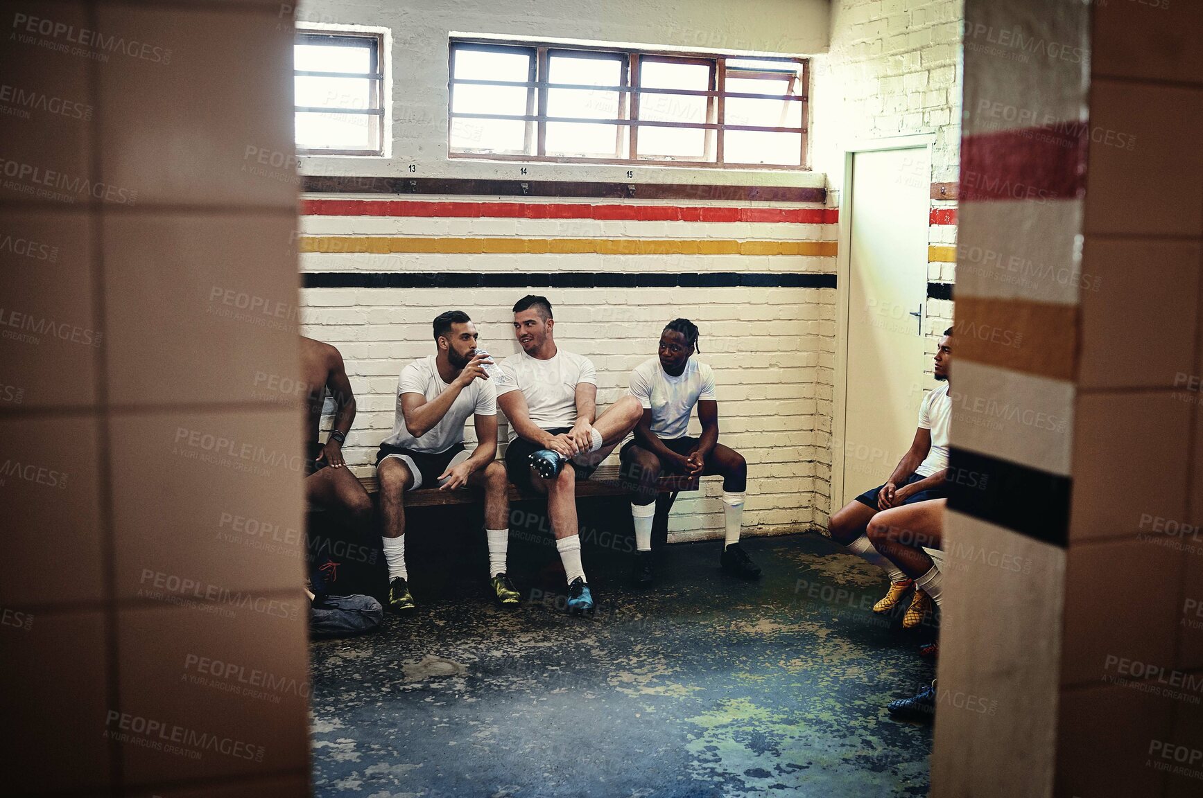 Buy stock photo Full length shot of a group of handsome young rugby players having a chat while sitting together in a locker room