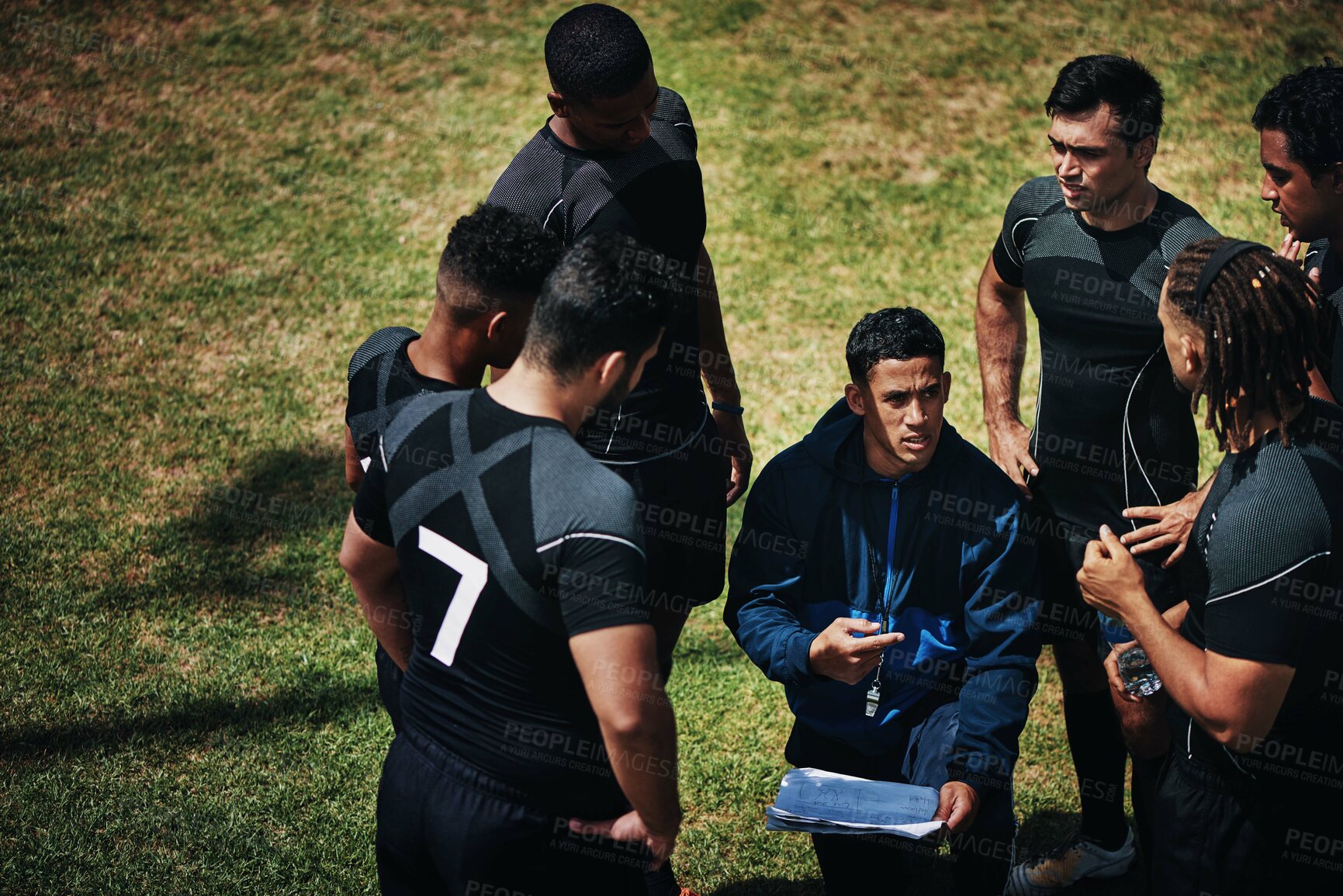 Buy stock photo Cropped shot of a handsome young rugby coach addressing his team on the field during the day