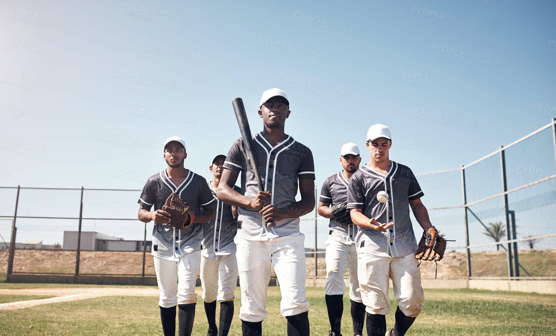 Buy stock photo Shot of a group of young men walking onto a baseball field