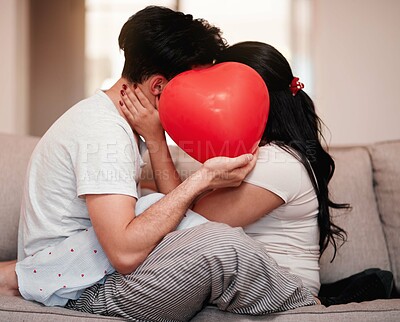 Buy stock photo Cropped shot of an unrecognizable young couple kissing behind a heart-shaped balloon on valentine's day