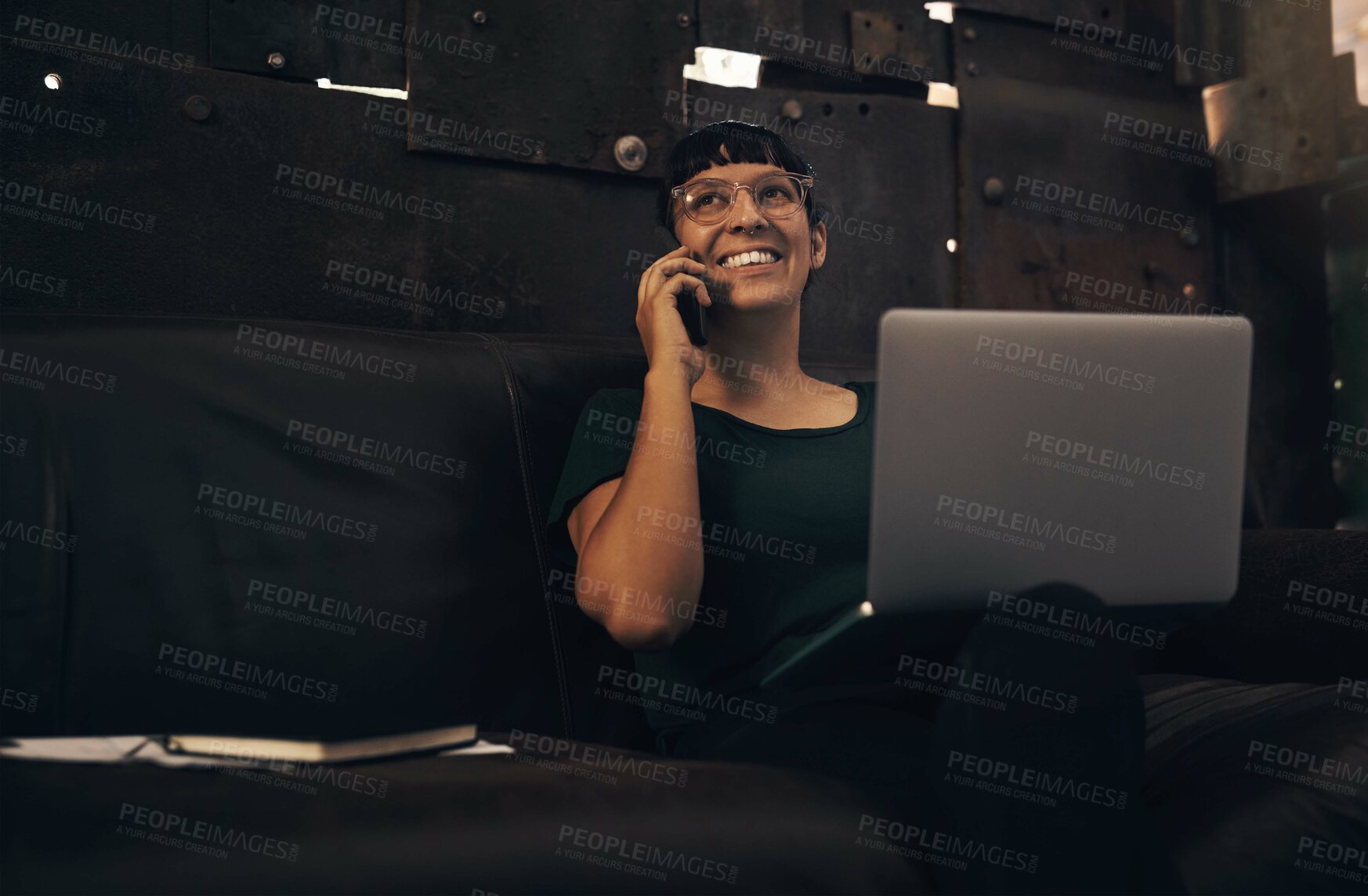Buy stock photo Shot of a young woman using a laptop and smartphone while working at a foundry