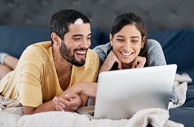 Buy stock photo Shot of a young couple using a laptop together in bed