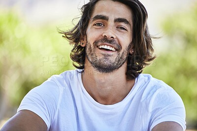 Buy stock photo Shot of a young man sitting and smiling outside in the park