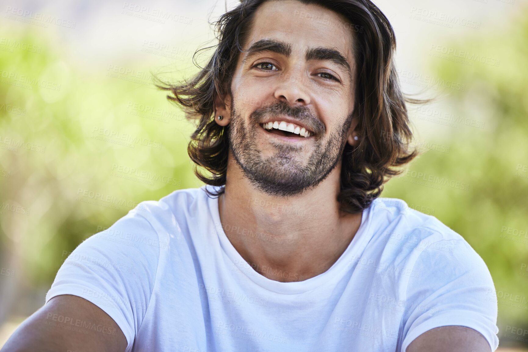 Buy stock photo Shot of a young man sitting and smiling outside in the park