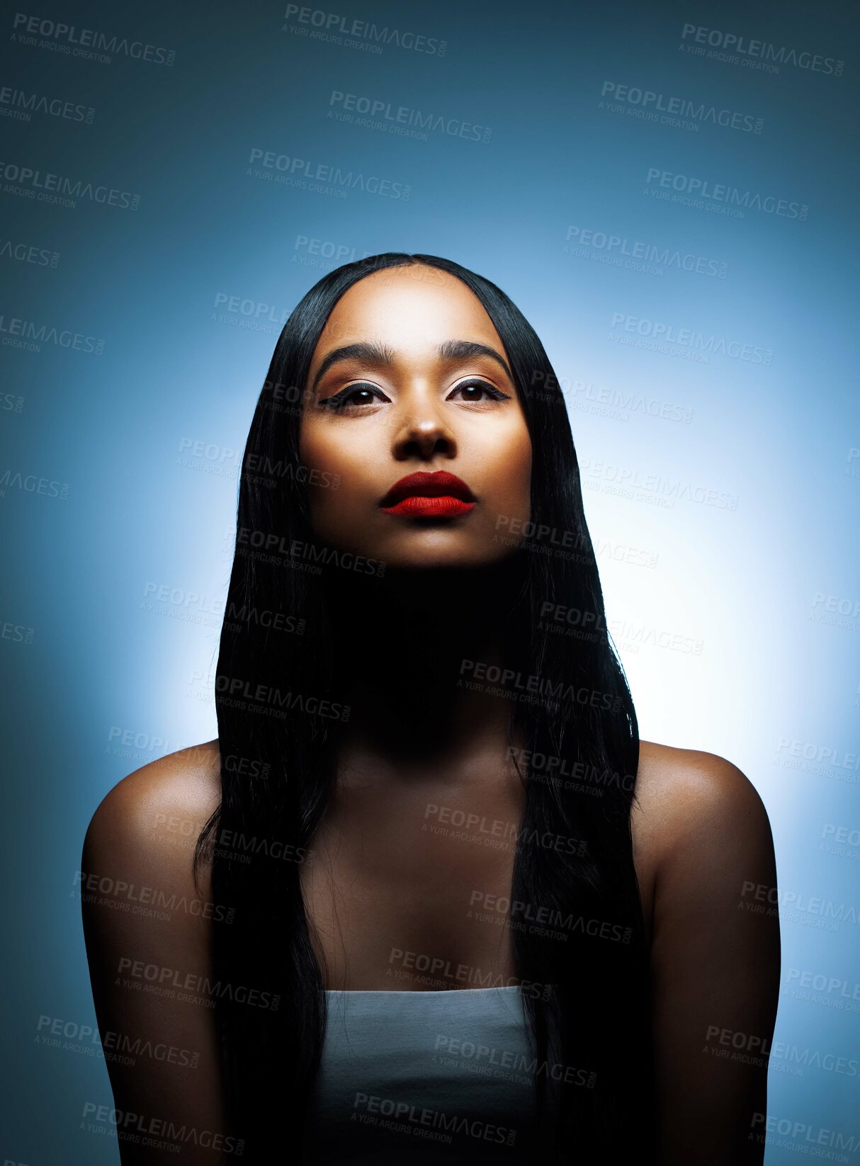 Buy stock photo Shot of an attractive young woman posing against a blue background in the studio