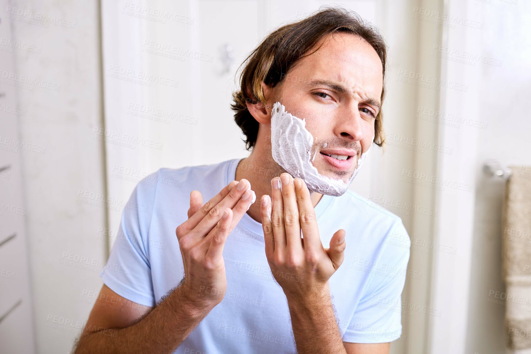 Buy stock photo Shot of a young man applying shaving foam to his face