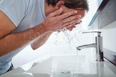 Buy stock photo Shot of a man washing his face in the bathroom sink