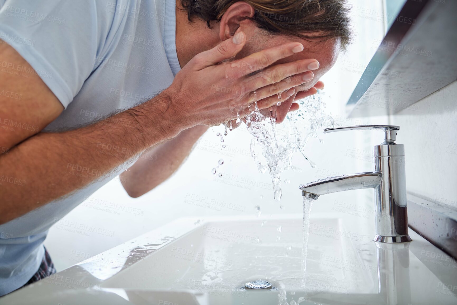 Buy stock photo Shot of a man washing his face in the bathroom sink