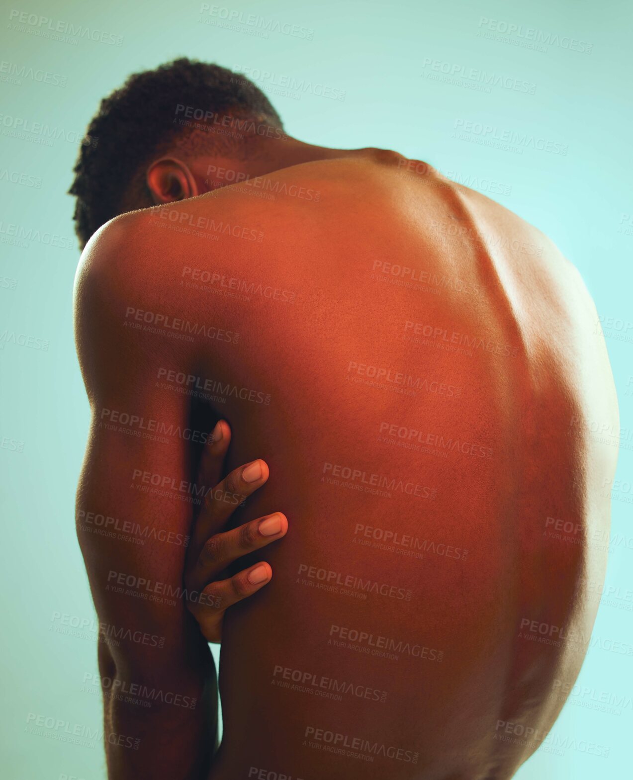 Buy stock photo Rearview shot of a man posing shirtless against a blue background