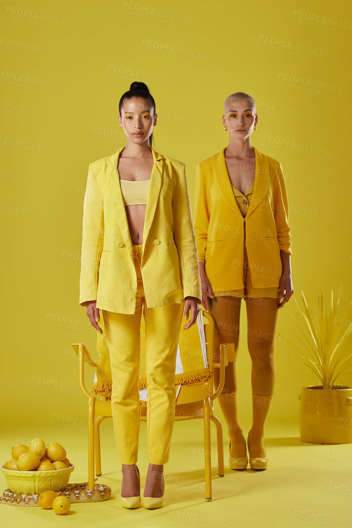 Buy stock photo Shot of two women dressed in stylish yellow clothes against a yellow background