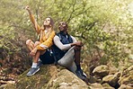 Hiking, freedom and couple relax on rock while looking at the nature, trees or calm sky outdoors. Relax and motivation with man and woman on sports, fitness and health and wellness mindset walk 