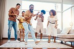 Energy, entertainment and friends singing karaoke in the living room with a microphone to music, playlist or radio. Happy, diversity and young people dancing, bonding and having fun together at home.