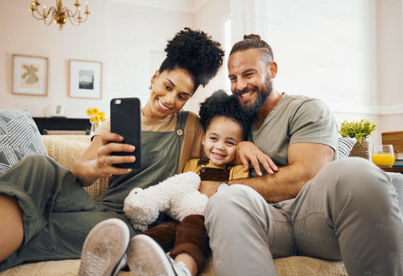 Buy stock photo Interracial parents, child and selfie on sofa, smile and hug for love, bonding and memory on web blog. Mom, dad and kid for photography, profile picture and happy for social media app in family house