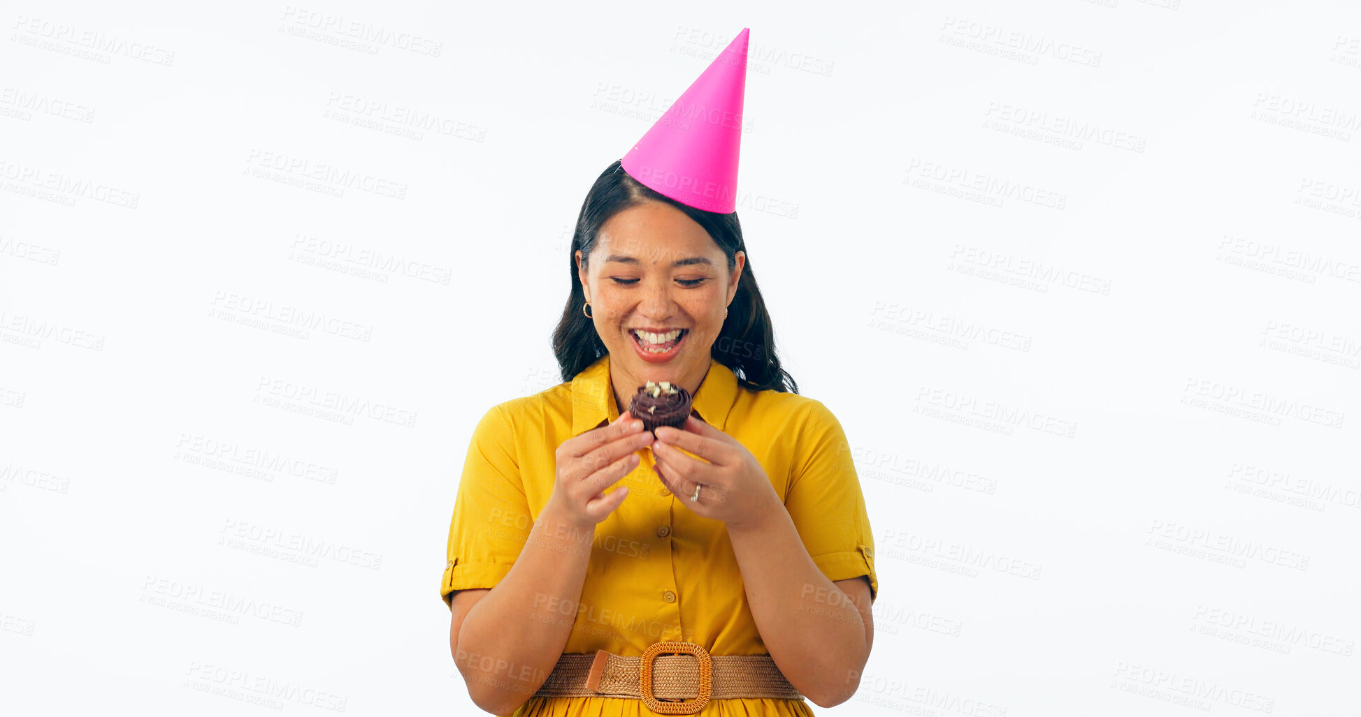 Buy stock photo Birthday party, chocolate and an asian woman eating a cupcake in studio isolated on a transparent background for celebration. Smile, hat and a happy young person with a dessert or snack at an event