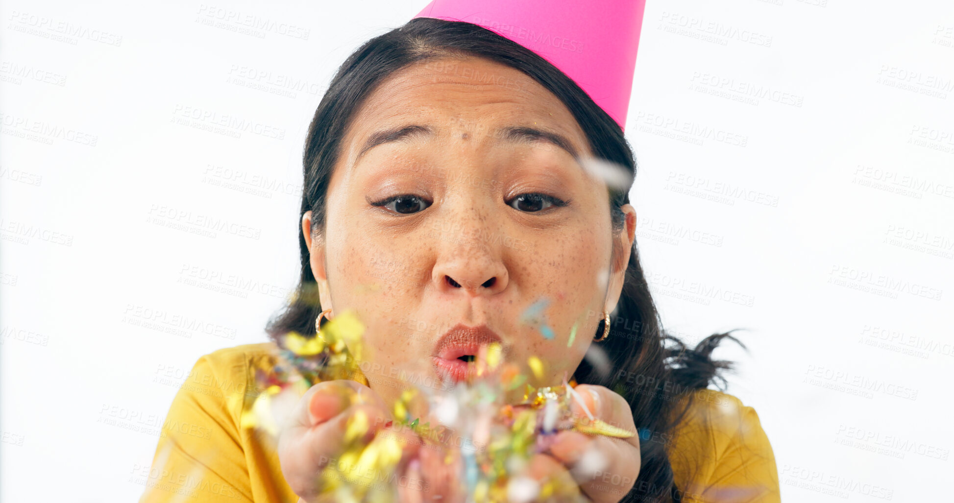 Buy stock photo Woman, party hat and blow confetti for birthday celebration, happy and excited in studio mockup. Asian person, smile and festive for winner of prize, giveaway and congratulations by white background 