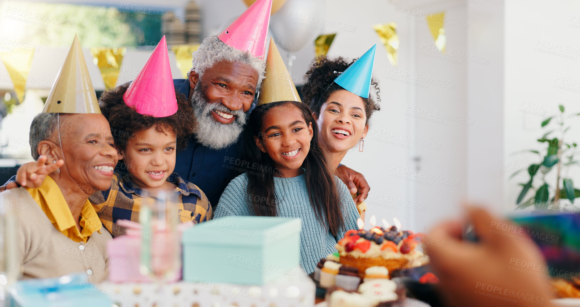 Buy stock photo Cake, happy and family at birthday party celebration together at modern house with candles. Smile, excited and young children with African father and grandparents with hats for photograph at home.