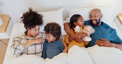 Buy stock photo Happy, relax and children with parents in bed of home for bonding together with teddy bear and top. Smile, fun and young interracial man and woman laying for rest with kids in bedroom of family house