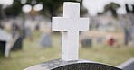 Funeral, graveyard and cross on tombstone for death ceremony, religion or memorial service. Catholic symbol, background or Christian sign on gravestone for mourning, burial or loss in public cemetery