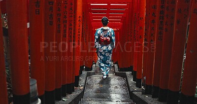 Woman, shinto religion and walk by gates in japan, spiritual path and indigenous culture in kimono. Person, traditional clothes or worship in peace, respect or beauty by Fushimi Inari Taisha in kyoto