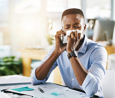 Buy stock photo Shot of a young businessman making use of tissues for his cold while trying to work in the office