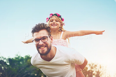 Buy stock photo Shot of a happy father giving his daughter a piggyback ride outside in nature