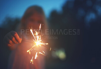 Buy stock photo Shot of a unrecognizable little girl playing with a sparkler at night time outside in nature