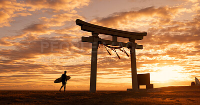 Buy stock photo Torii gate, sunset and man with surfboard, ocean and travel adventure in Japan with orange sky. Shinto architecture, Asian culture and calm beach in Japanese nature with person at spiritual monument.