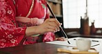 Ink, calligraphy and hands of Japanese woman in home for traditional script, paper and documents. Creative, Asian culture and person with vintage paintbrush tools for writing, font and text in house