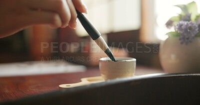 Buy stock photo Brush, closeup and hands at a table for calligraphy, writing or ancient Japanese art in a house. Letter, communication and zoom on person fingers with traditional ink stroke, penmanship or art tool