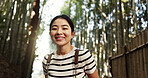 Japanese woman, portrait and hiking in forest with smile, pride and backpack for travel on holiday in bush. Girl, person and happy with bamboo plants, freedom and outdoor by trees, woods or nature