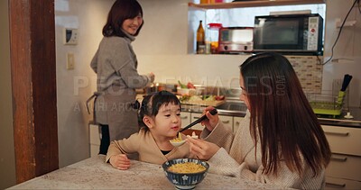 Buy stock photo Family, Japanese and mother feeding daughter in kitchen of home for growth, health or nutrition. Food, girl eating ramen noodles in apartment with parent and grandparent for diet or child development