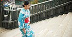 Stairs, woman in a city and walking with traditional outfit, travel and fresh air with wellness, comfort and peace. Japanese person, freedom and girl with culture, movement and thinking with clothes