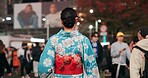 Back, city and Japanese woman on street at night with crowd for culture, heritage or tradition. Travel, kimono and person walking outdoor on street of urban Tokyo town for vacation or sightseeing