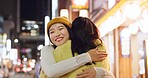 Woman, friends and hug in Japanese city or happy reunion for party night, adventure or Tokyo. Female people, embrace and dark or bokeh on street with light or international travel, journey or evening