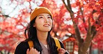 Japanese, woman and travel with autumn nature, trees and red leaves in Kyoto forest with happiness. Girl, smile and walk in park, woods with orange environment or adventure in colorful zen garden
