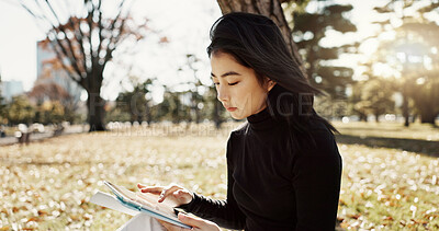 Buy stock photo Japanese woman, reading and book on lawn, thinking and relax by tree, park or sunshine with peace. Girl, person or student with story in nature, college or idea with vision, knowledge or campus grass