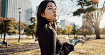 Japanese, woman and smartphone in park, travel and communication with social media and adventure. Texting, email and online chat with connectivity, mobile app and outdoor for fresh air in Tokyo