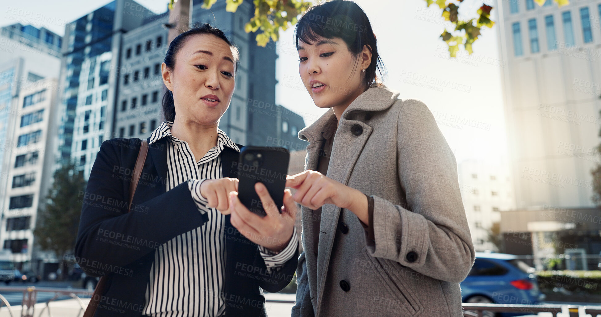 Buy stock photo Phone, city and Japanese business woman planning together for travel, journey or commute. Collaboration, talking or discussion with employee team reading text message communication outdoor in Tokyo
