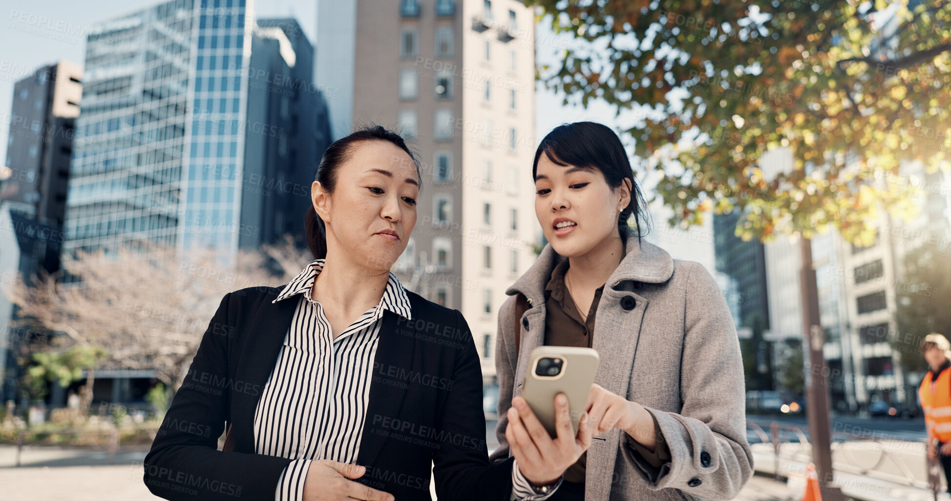 Buy stock photo Phone, city and Japanese business woman walking to work together for travel, journey or commute. Collaboration, planning and discussion with employee team reading text message outdoor in Tokyo